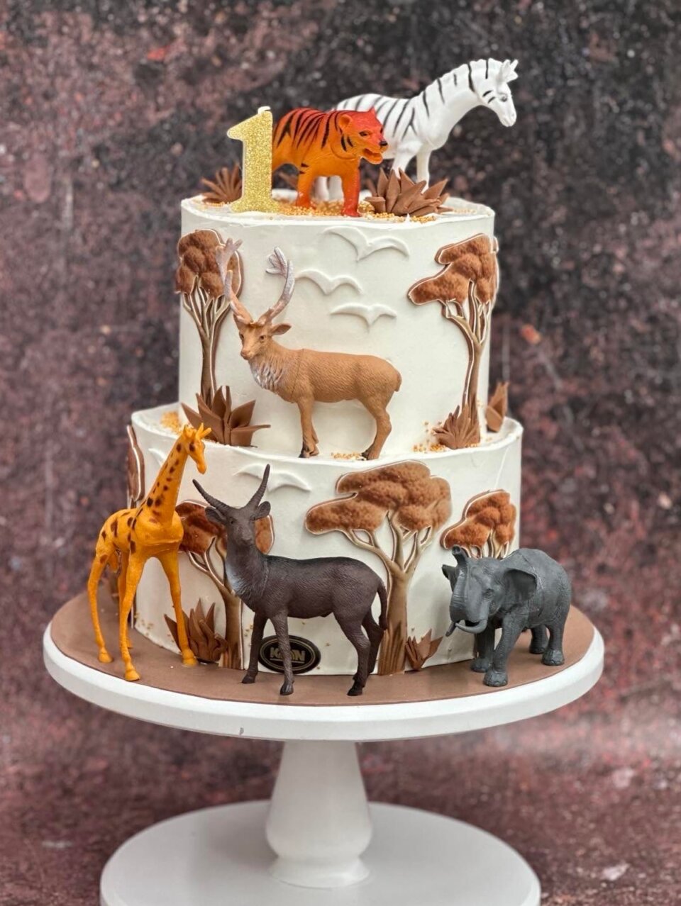 Dvospratna bela torta sa figurama safari životinja i drvećem