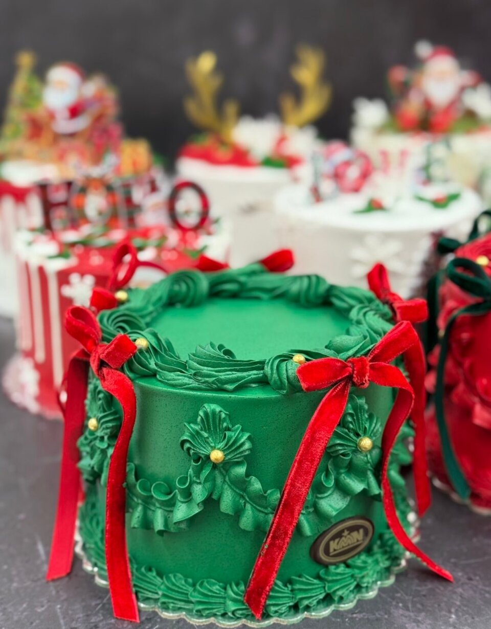 Zelena praznična torta sa crvenim mašnama i zlatnim perlama