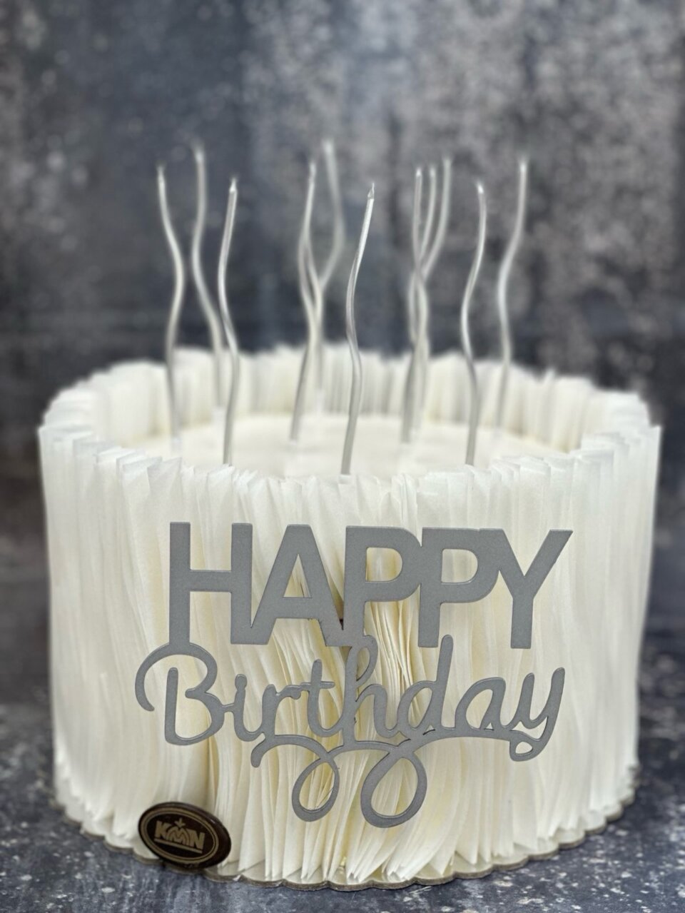 Bela torta sa Happy Birthday natpisom i srebrnim svećicama