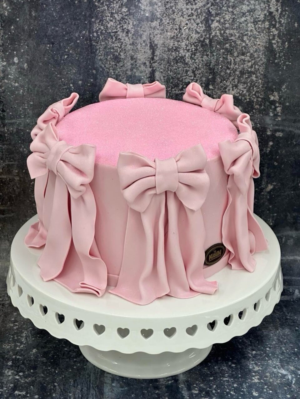 Roze torta sa šećernim mašnama i draperijom