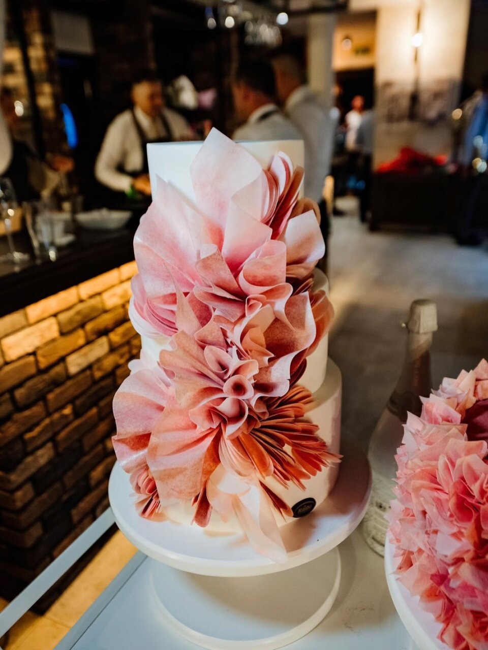 Trospratna bela svadbena torta sa velikim roze cvetom od jestivog papira