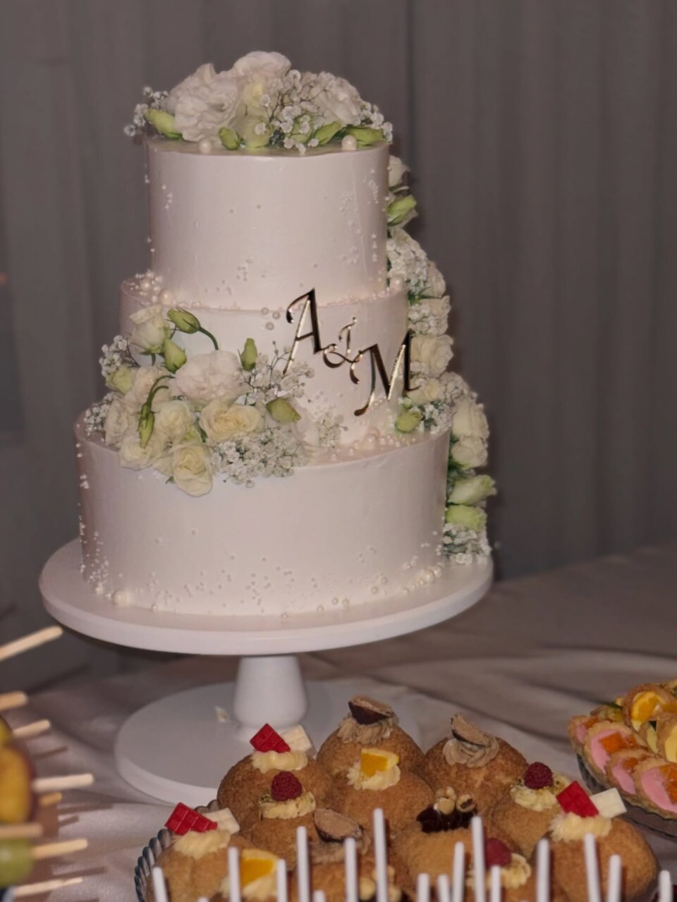 Trospratna bela svadbena torta sa monogramom i belim ružama